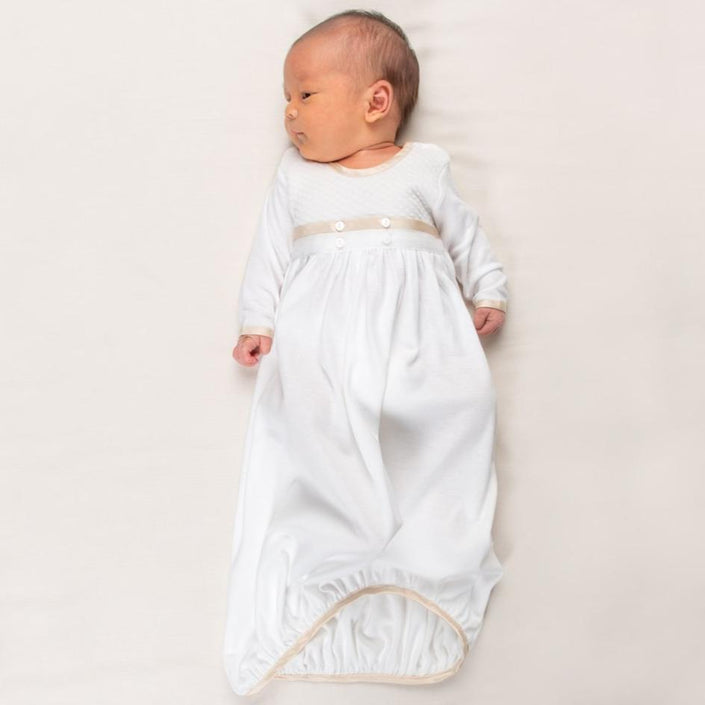 Newborn baby boy wearing the Liam Cotton Newborn Gown crafted from soft white pima cotton, ivory quilted cotton bodice, and detailed with silk trim in a shade of champagne