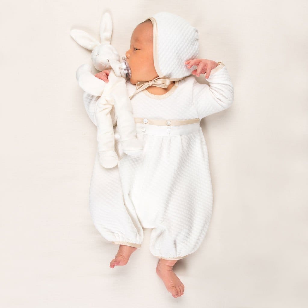 Photo of a newborn baby wearing the Quilted Newborn Romper and holding a stuffed animal bunny