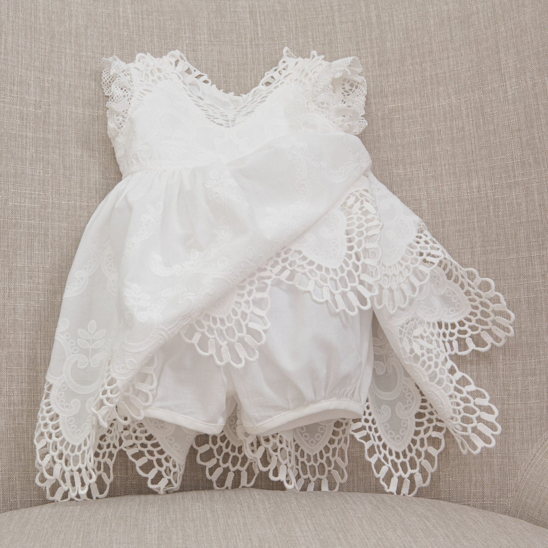 Flat lay photo of the Lily Christening Romper Dress showcasing the romper underneath the dress 