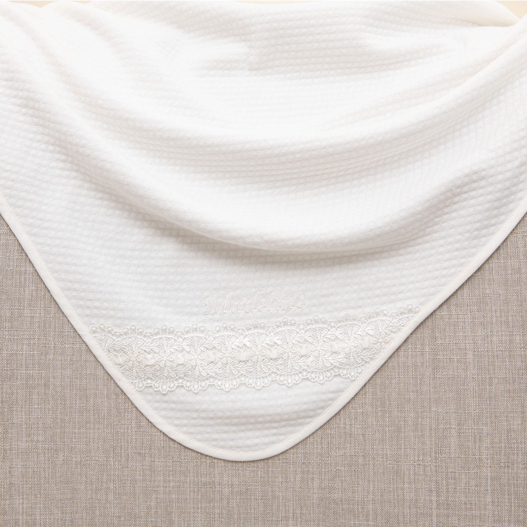 A white textured fabric with a delicate lace trim drapes over a neutral-toned surface, capturing the elegance of the Madeline Accessory Bundle - Save 15%.
