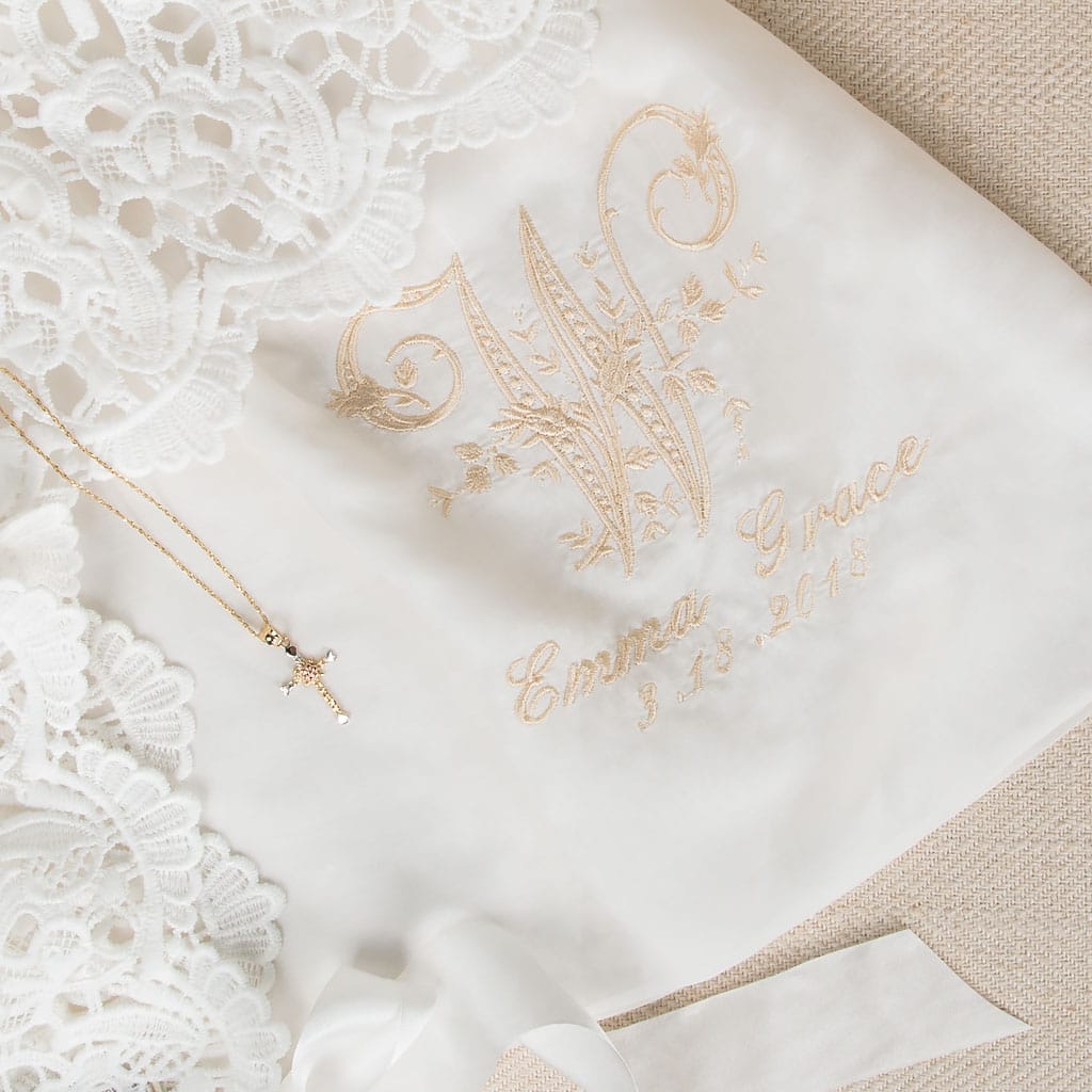 Close-up of the embroidered monogram on the Lola Christening Gown, featuring an elegant 'W' initial, with the name 'Emma Grace' and the date '3-13-2018,' showcasing christening personalization options.