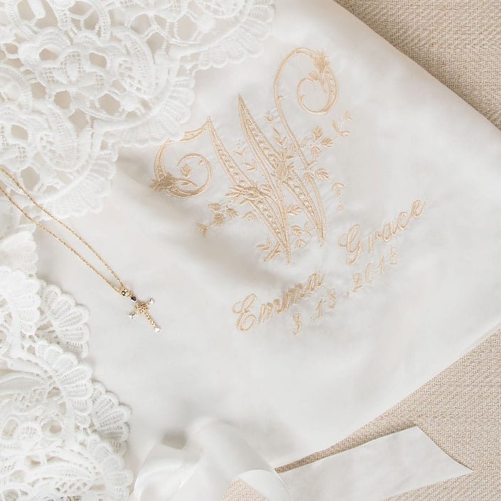 Close-up of the embroidered monogram on the Lola Christening Gown, featuring an elegant 'W' initial, with the name 'Emma Grace' and the date '3-13-2018,' showcasing christening personalization options.