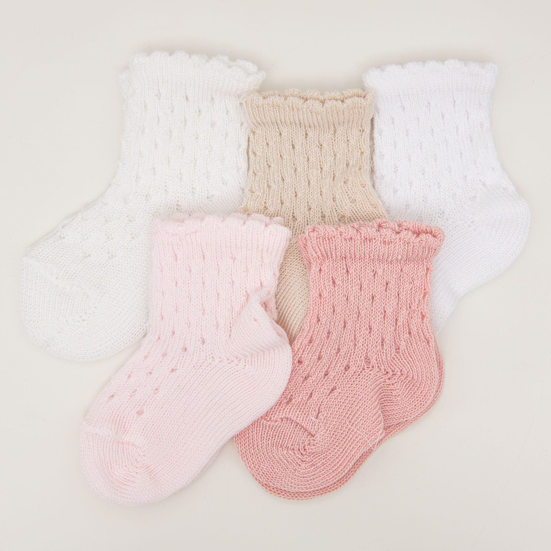 Five pairs of Scallop Edge Crochet Socks, made from 100% cotton, are displayed in a semicircle. The socks are available in white, beige, light pink, and darker pink colors. Each pair features a delicate pattern and scalloped cuffs for an extra touch of charm.