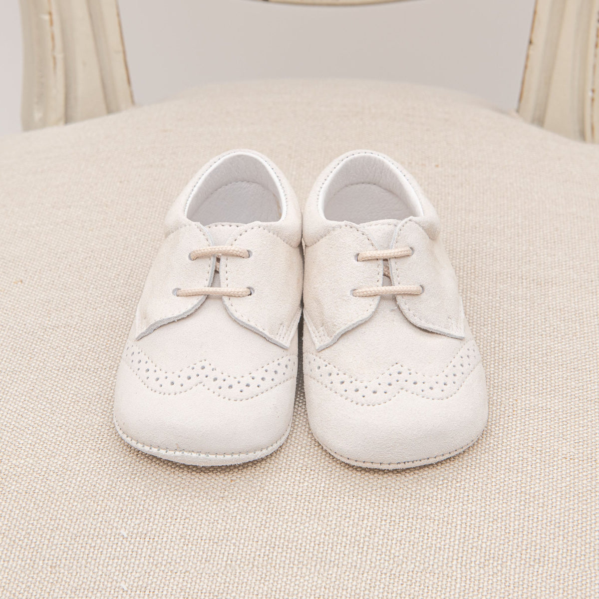 Photo of the Tan Suede Shoes on a chair. They are made with tan suede leather and feature detailed edging