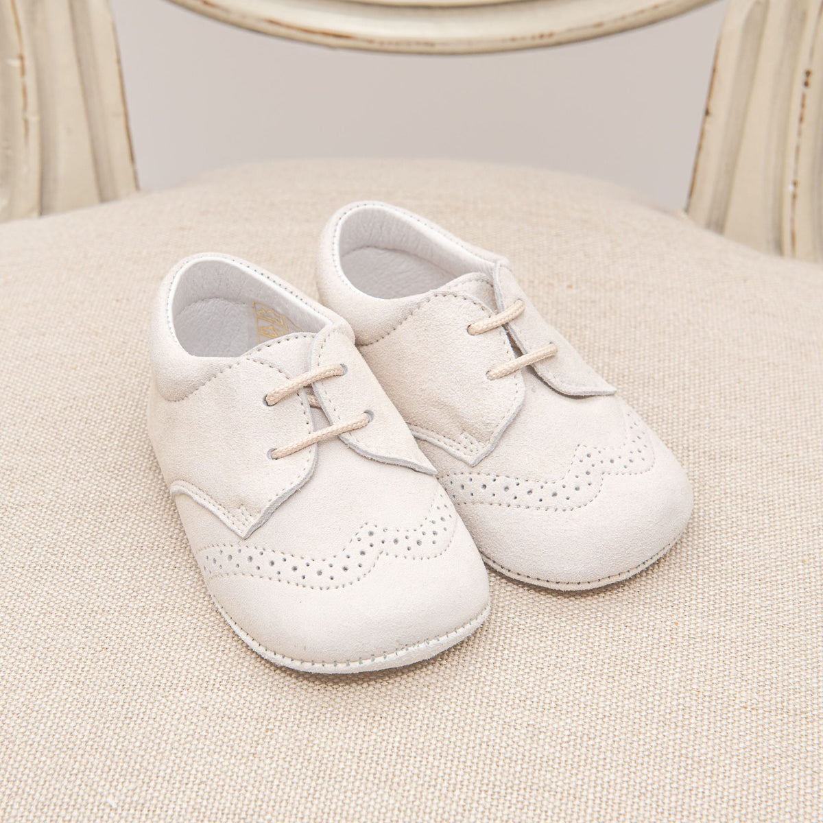 Photo of the Tan Suede Shoes on a chair. They are made with tan suede leather and feature detailed edging