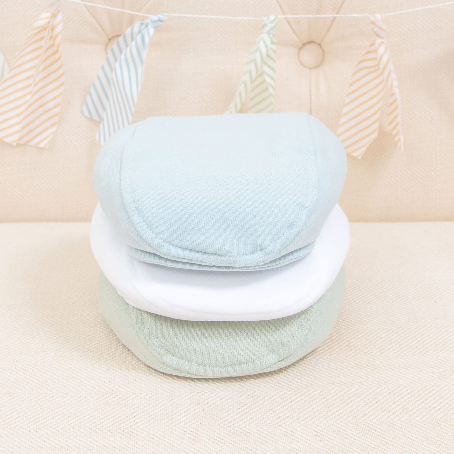 Flat lay photo of the the three Theodore Newsboy Caps in blue, green, and white.