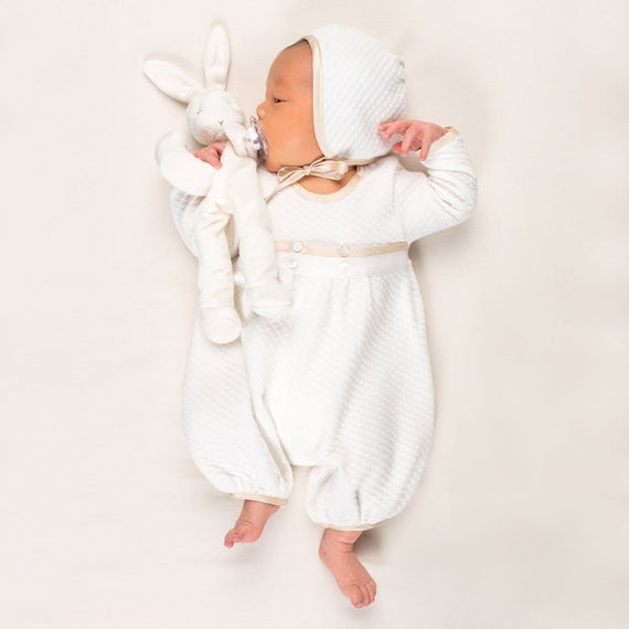Photo of a newborn baby wearing the Quilted Newborn Romper and holding a stuffed animal bunny