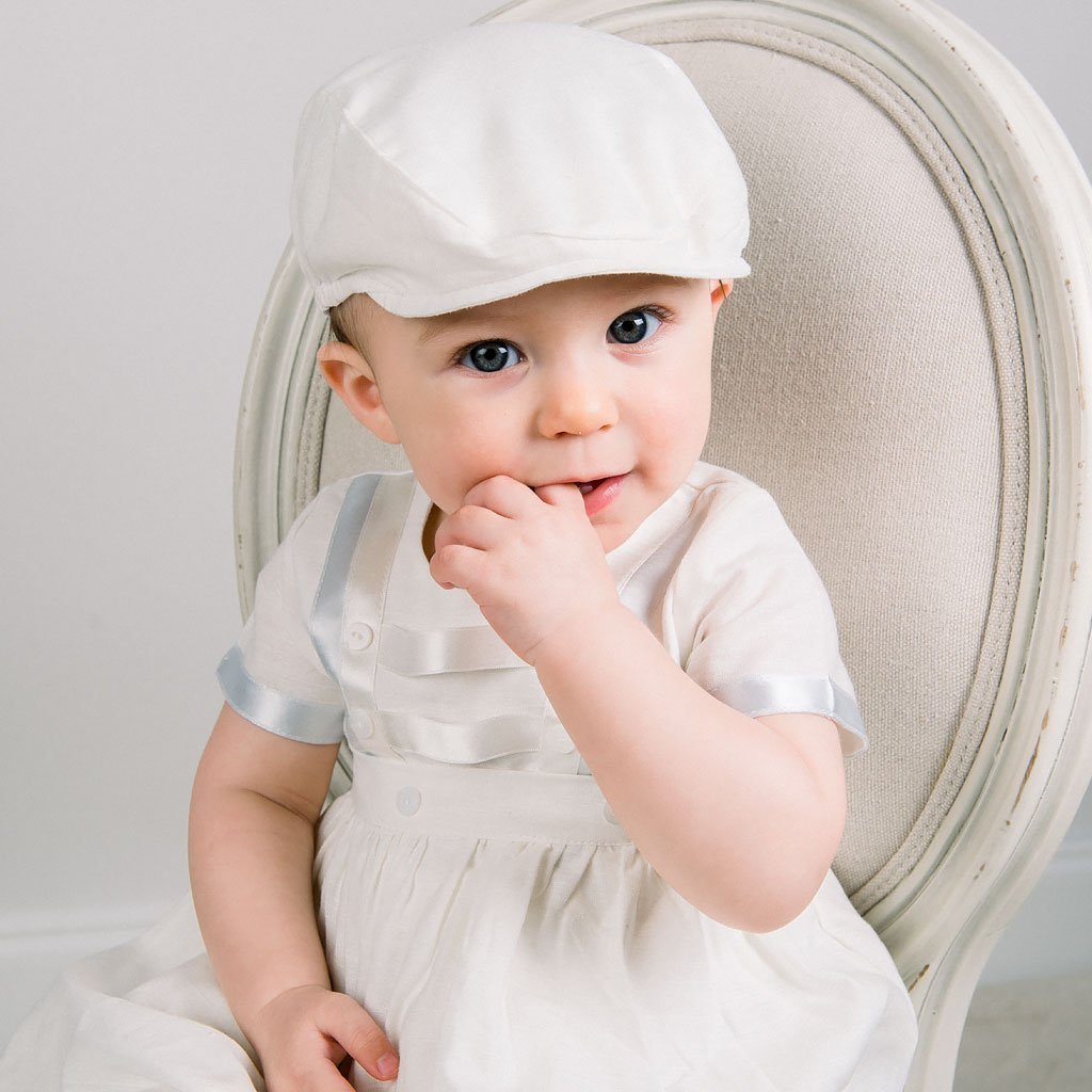 Baby boy sitting on a chair. He is wearing the Owen Convertible Romper and Skirt Set.
