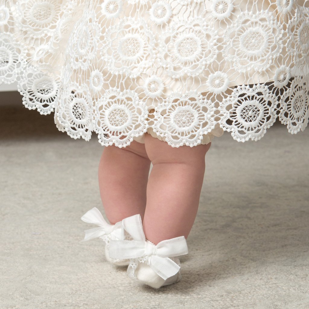 Baby girl standing. Photographic detail of the dem of the Poppy Blessing Dress.